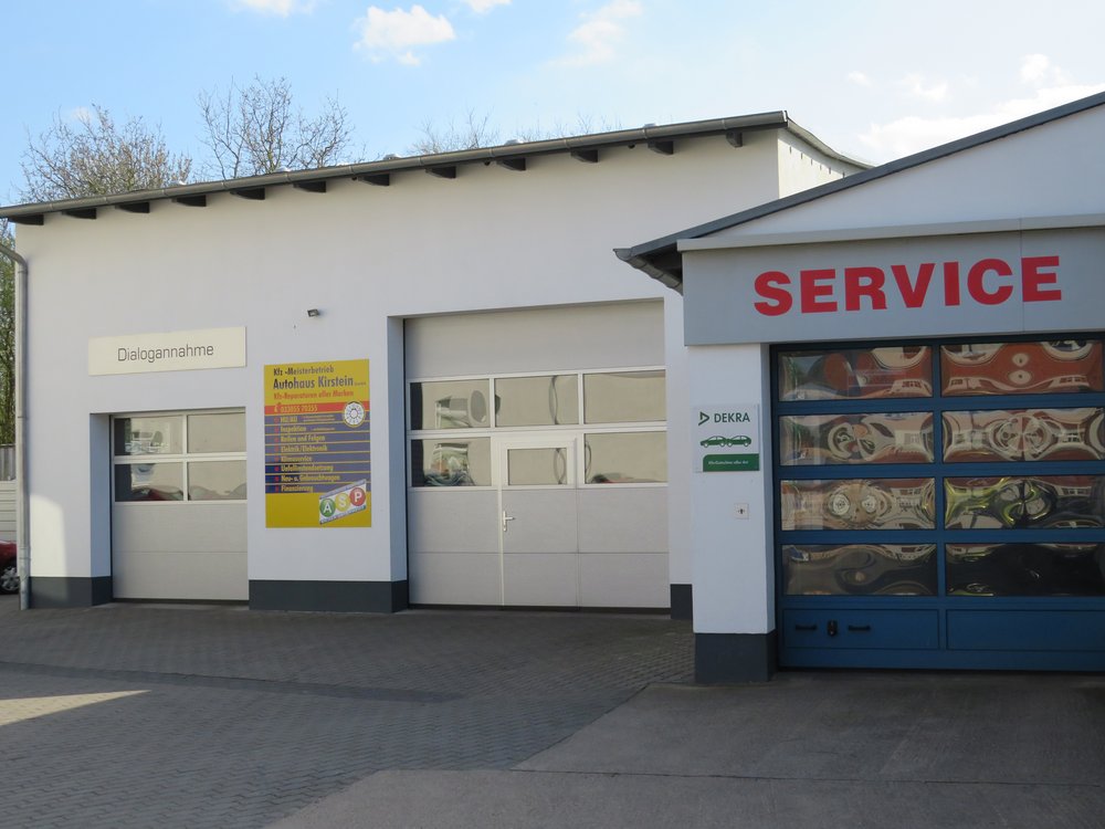 Eine Werkstattfassade mit mehreren Schildern und einer Übersicht der angebotenen Kfz-Leistungen.
